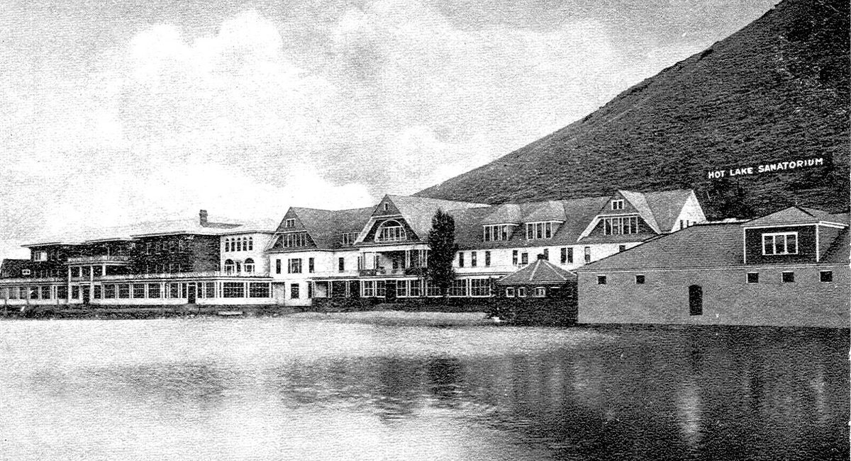 Black-and-white postcard view of the Hot Lake Sanatorium buildings along the shore of Hot Lake around 1915