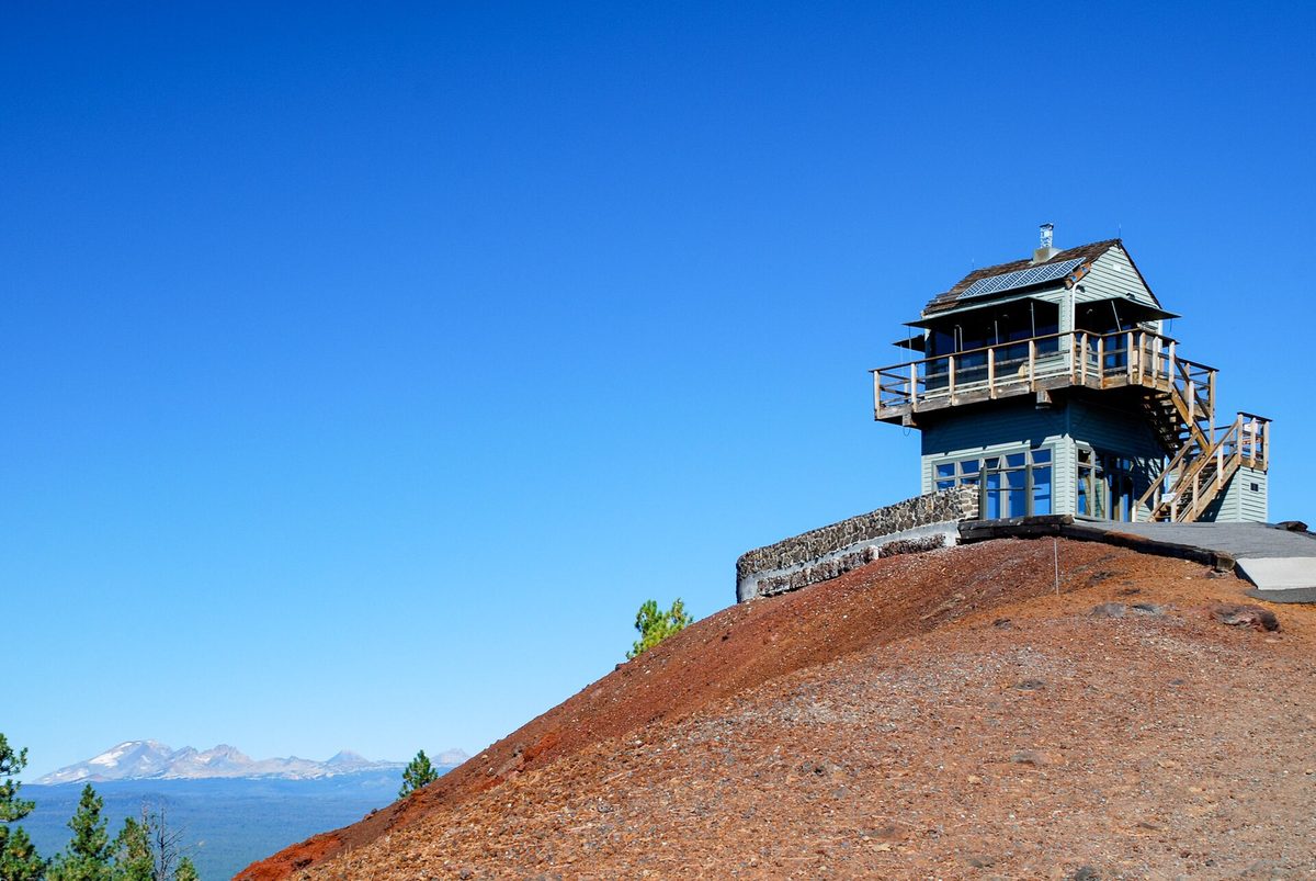 The fire lookout on the red cinder summit of Lava Butte under a blue sky