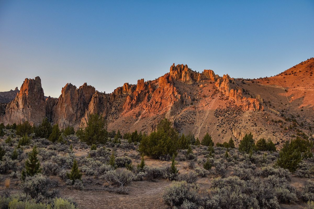 Orange tuff spires and cliffs of Smith Rock glowing in late light above sagebrush