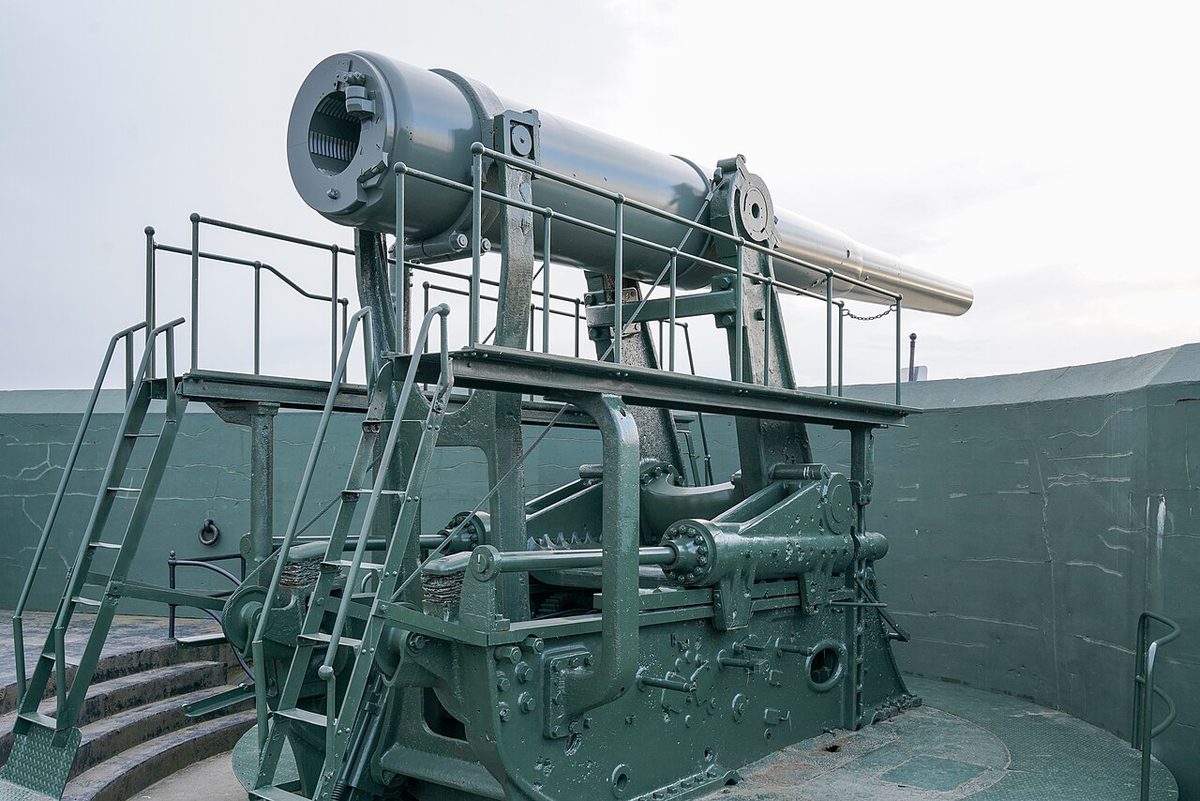 A green 10-inch coastal gun raised on its disappearing carriage inside a concrete gun pit at Fort Casey