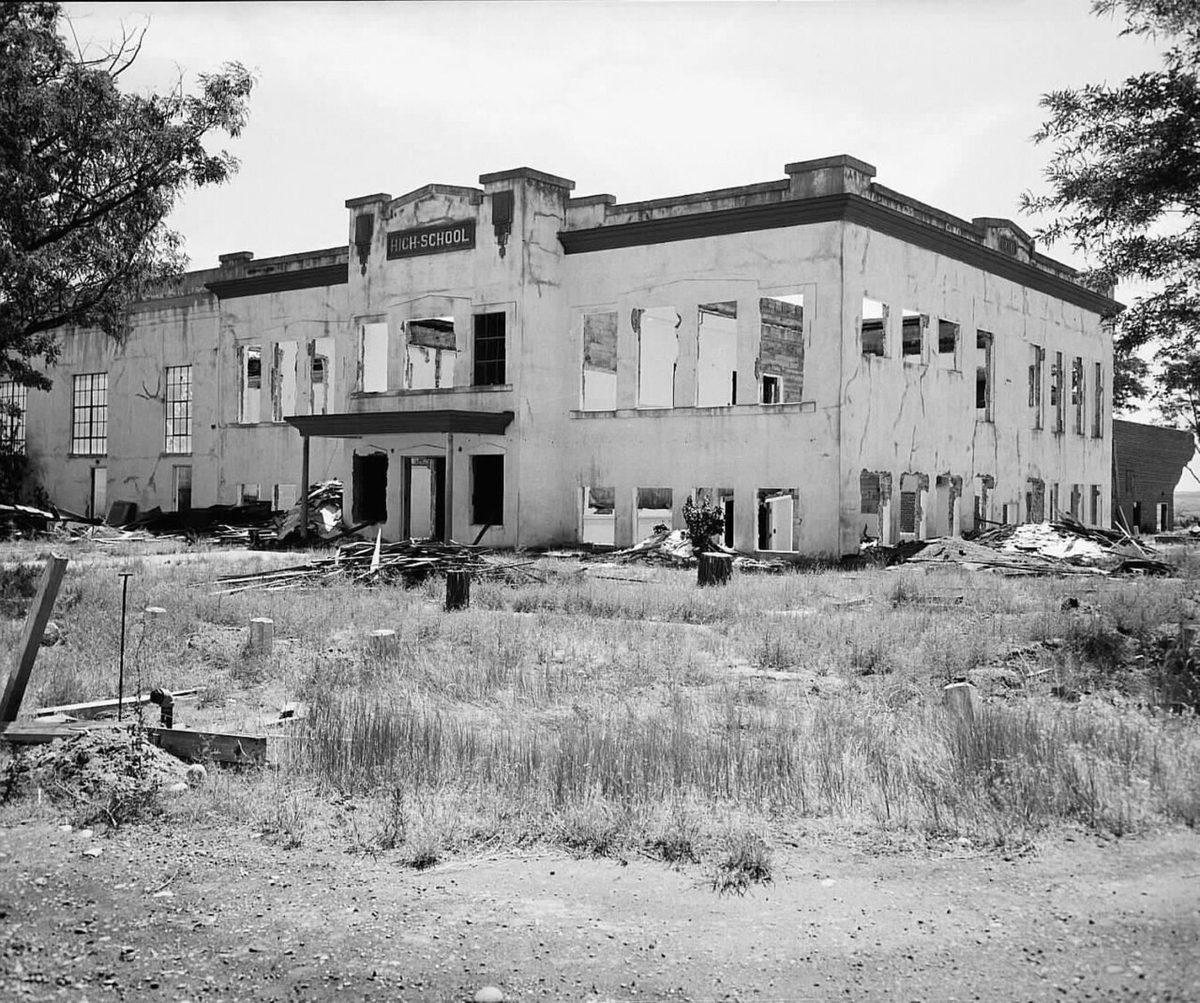Black-and-white photo of the empty two-story Hanford High School building with dry grass in front