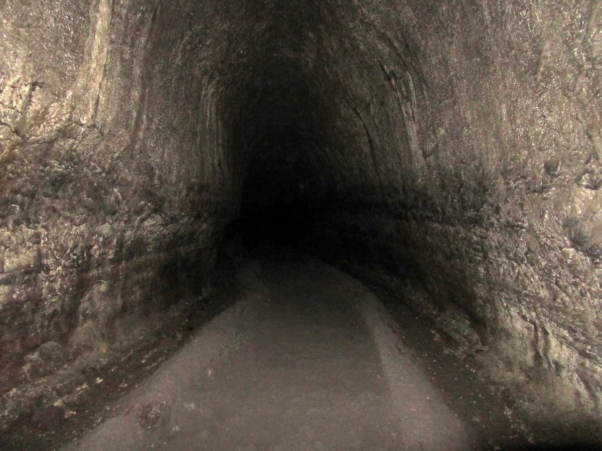 A long, round lava tube passage inside Ape Cave with a smooth floor fading into darkness